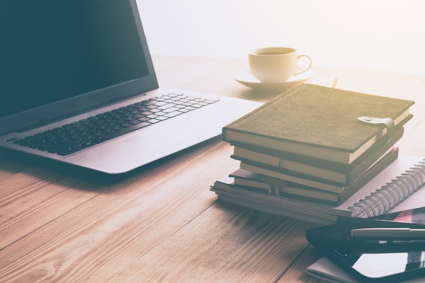 Laptop, tea cup and books on the table