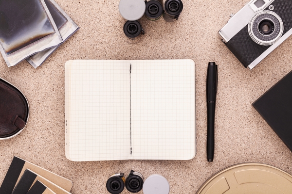 Note book, pen, camera on the desk table