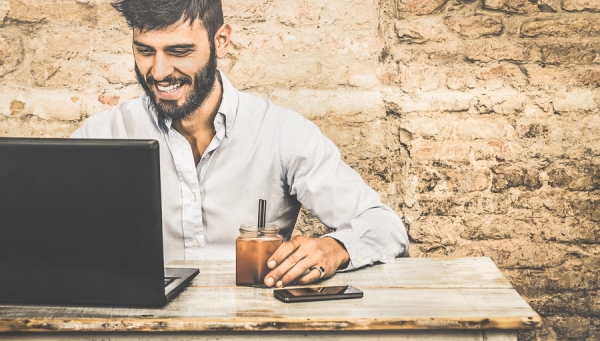 A smiling man working on the laptop