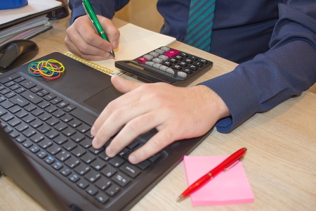Man working on the laptop and calculator on the table